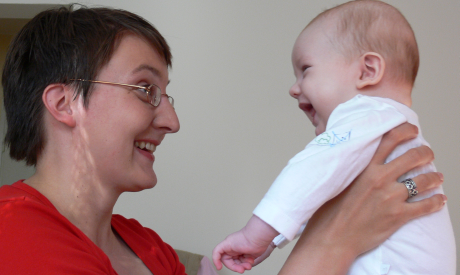äiti nostaa vauvaa ilmaan ja molemmat nauravat sekä katsovat toisiaan silmiin