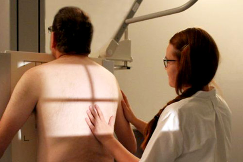röntgenhoitaja ohjaa potilaan röntgenlaitteen eteen.